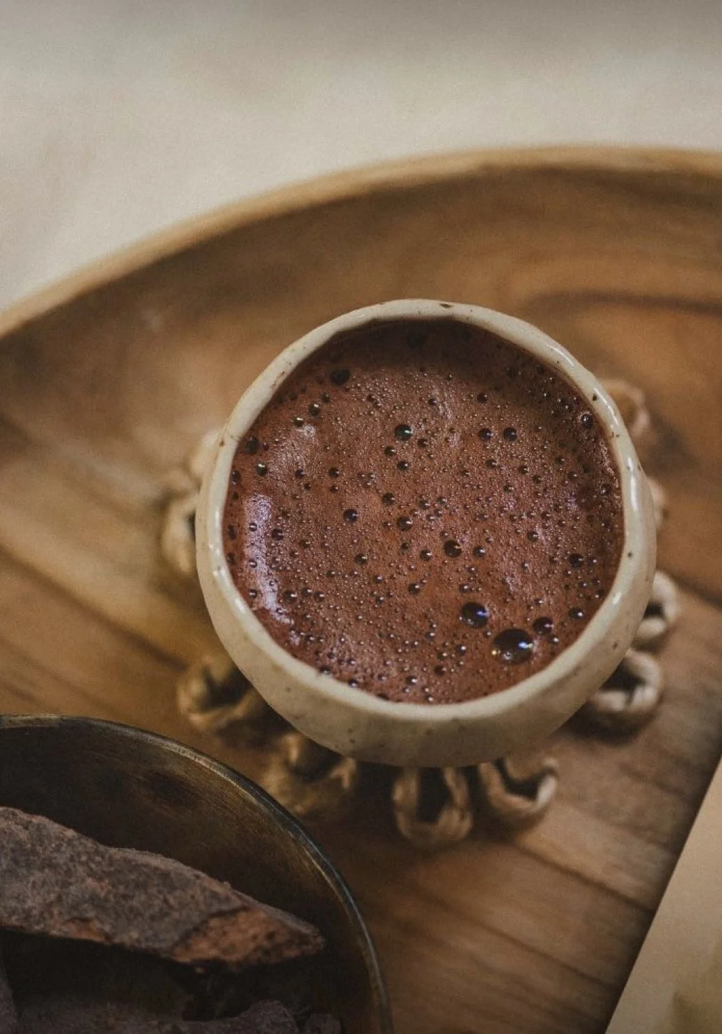 Small ceramic cup of frothy ceremonial cacao on a wooden tray